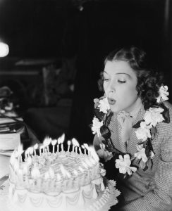 Profile of a young woman blowing off candles on a birthday cake (EV005818_H)