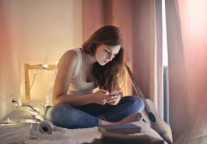 keder sig, kigger på mobil, sociale medier, pige i seng, TikTok (Foto: Pexels)